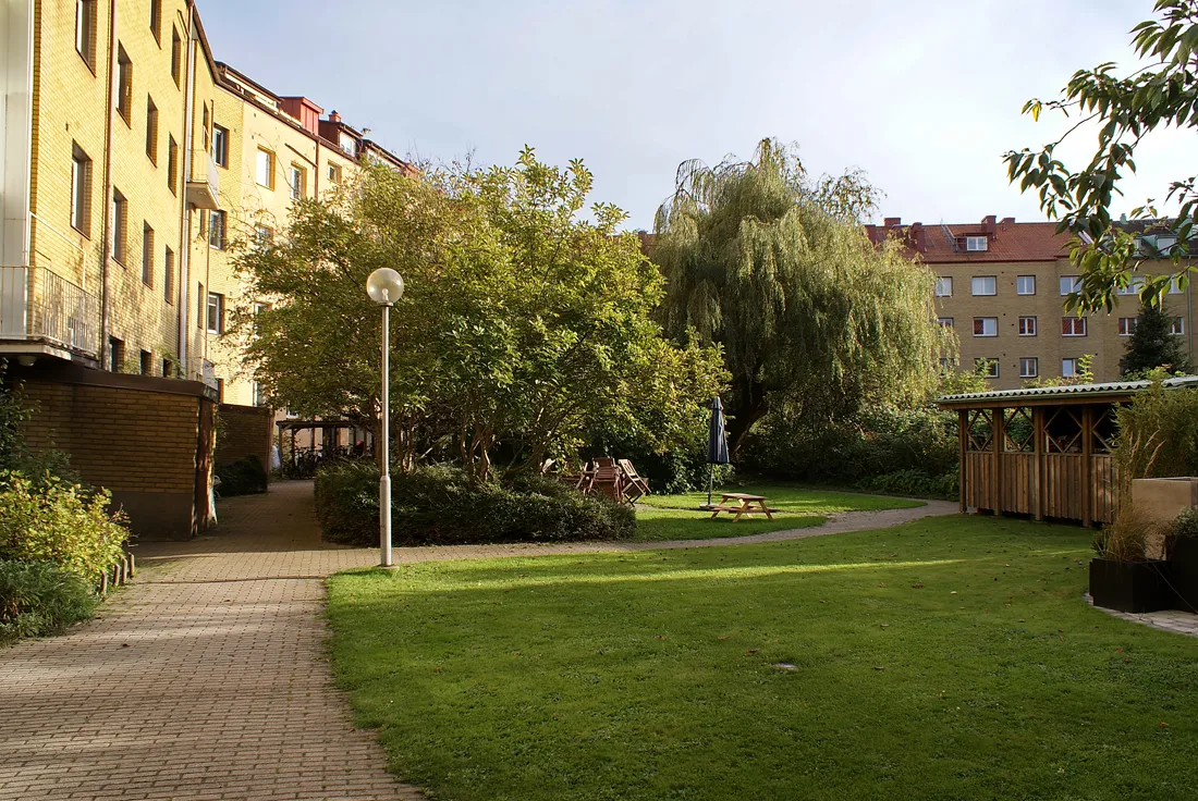Grön innergård med gräsmatta, träd och sittplatser vid Carl Hillsgatan 14 i Slottsstaden