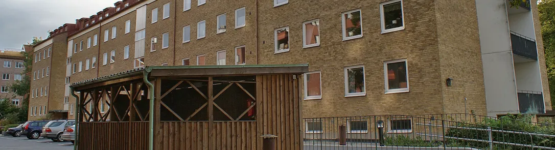Flerbostadshus i gult tegel med träpergola på Västra Rönneholmsvägen 74
