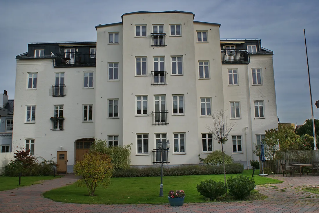Ljust putsat trevåningshus med trädgård på Odengatan 35 i Limhamn